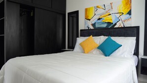 A hotel room with a large bed, a wardrobe, and a painting on the wall.