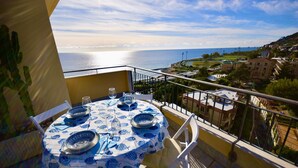 A round table with blue tablecloth and fish patterns, set with plates, glasses, and cutlery.