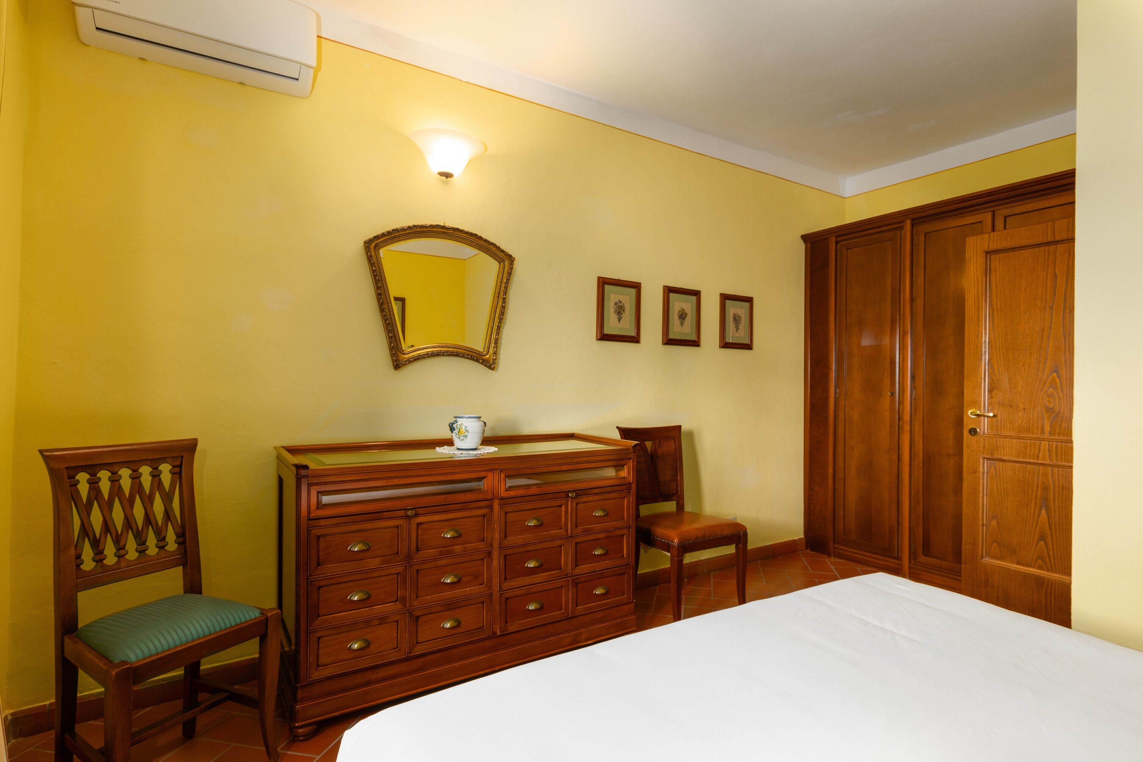 Une chambre à coucher comprenant un lit, une commode, des chaises, un miroir et une armoire.