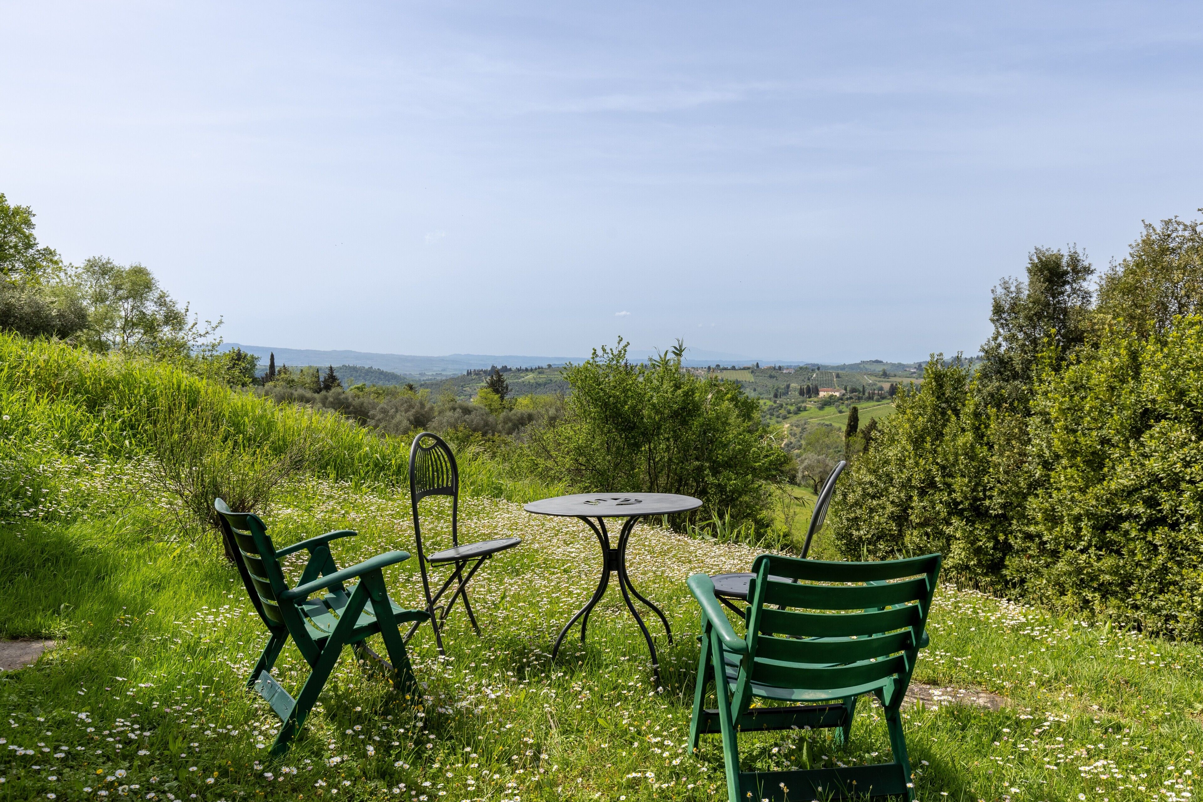 Un espace extérieur aménagé avec une table et des chaises, entouré de verdure et offrant une vue sur la campagne.