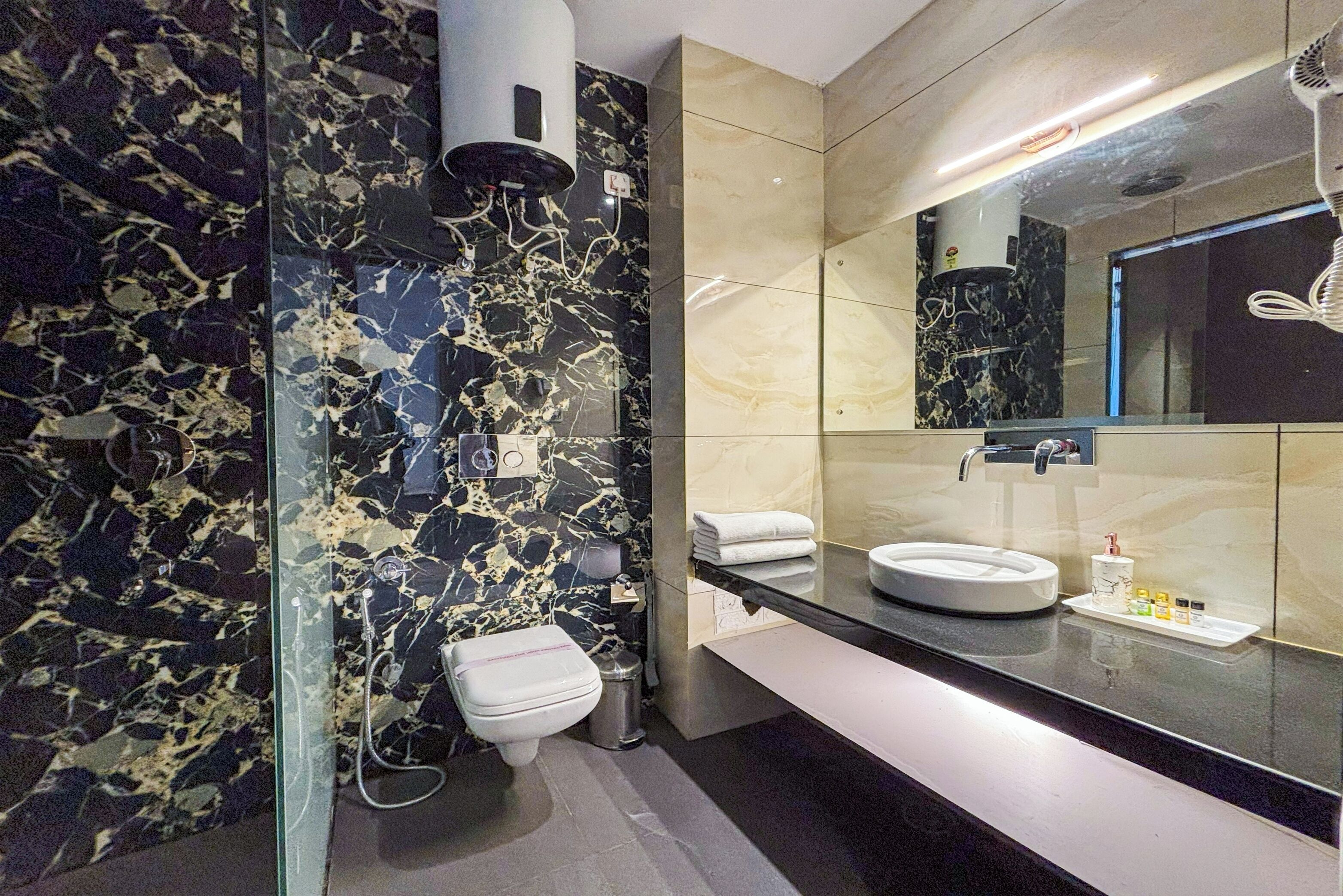 A modern bathroom with a glass partition, a white toilet, a sink with a mirror, and a towel rack.