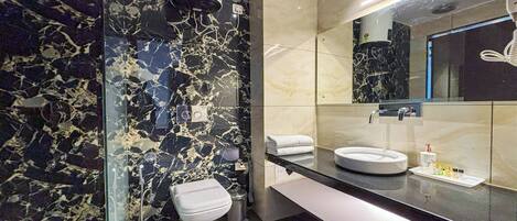 A modern bathroom with a glass partition, a white toilet, a sink with a mirror, and a towel rack.