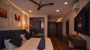 Une chambre d’hôtel moderne dotée d’un grand lit, d’un ventilateur de plafond, d’une télévision et offrant une vue sur la ville.
