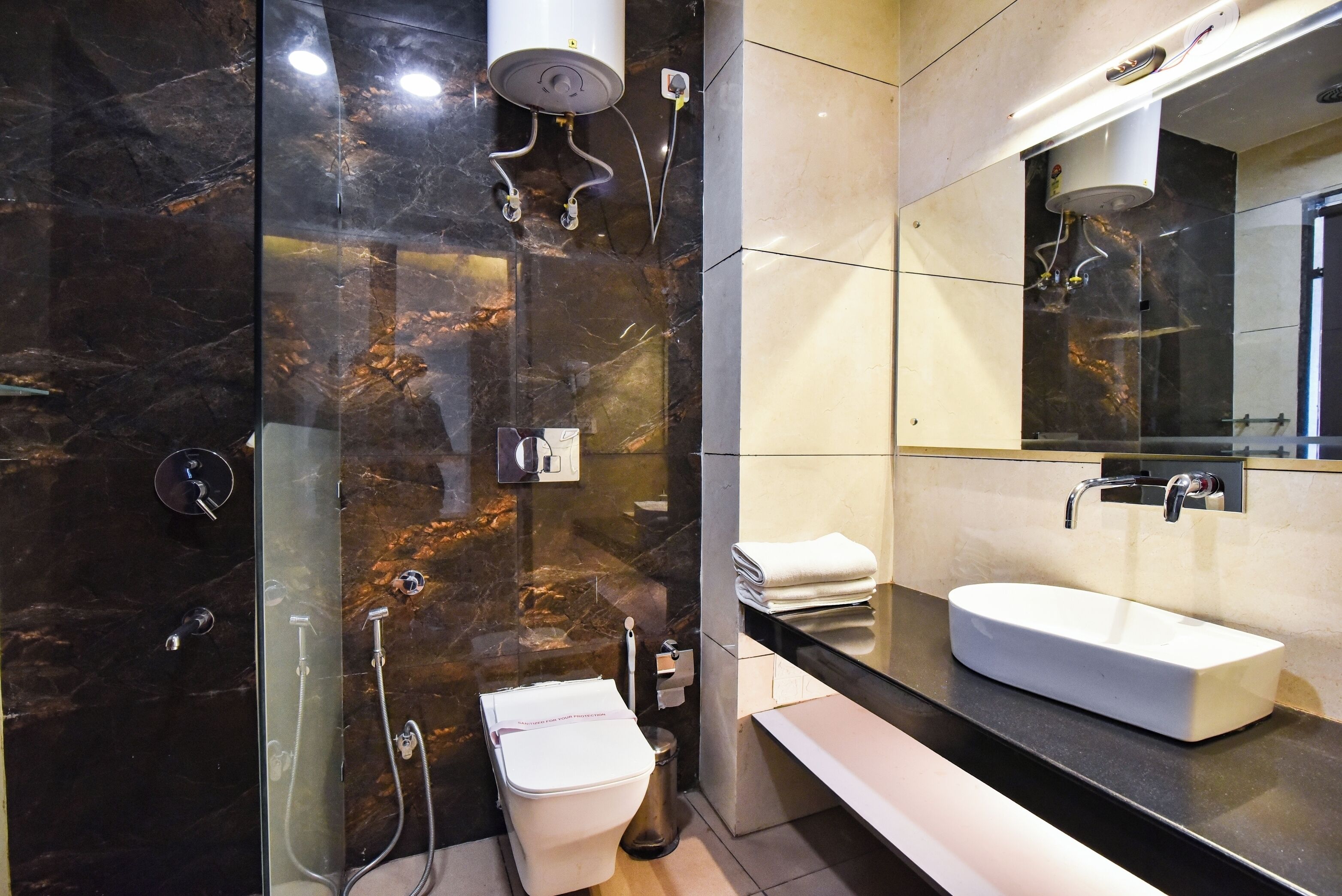 Une salle de bain moderne avec un mur en marbre, un lavabo blanc et une douche à parois de verre.