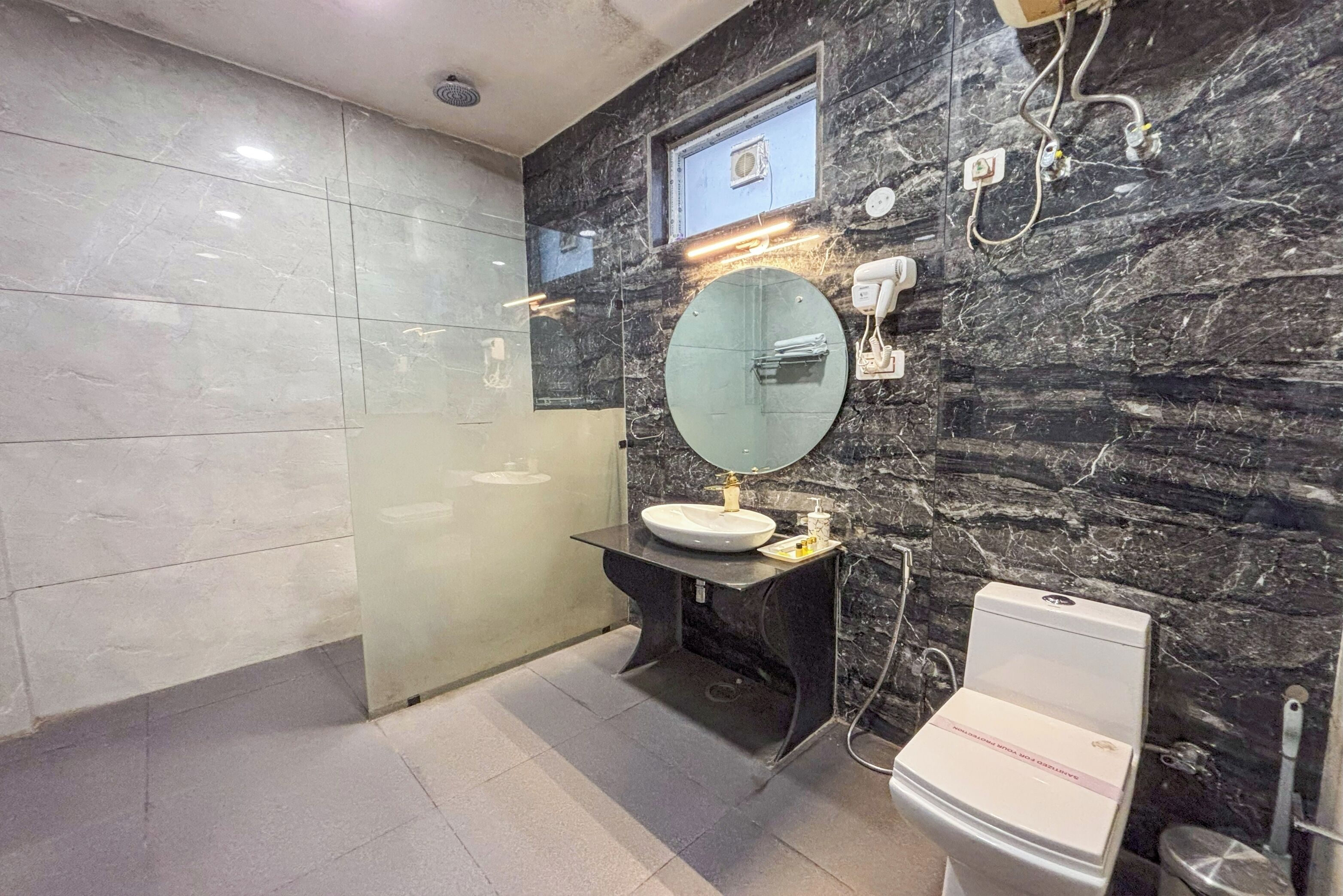 A modern bathroom with a marble vanity, a round mirror, and a toilet.