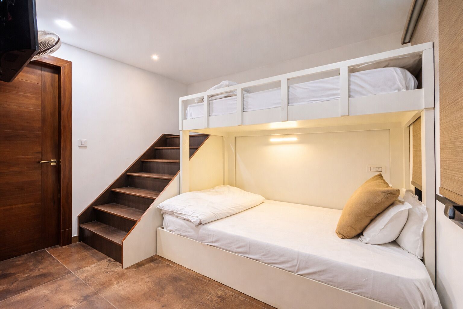 A bunk bed room with a wooden staircase and a door.