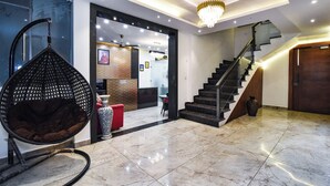 Un hall d’entrée moderne agrémenté d’un lustre, d’un fauteuil suspendu, d’un escalier et d’un comptoir d’accueil.