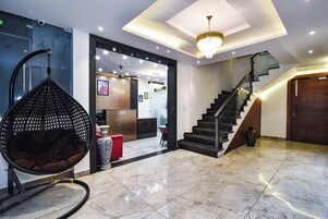 Un hall d’entrée moderne agrémenté d’un lustre, d’un fauteuil suspendu, d’un escalier et d’un comptoir d’accueil.