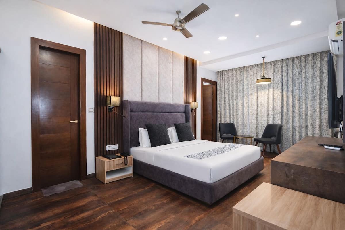 A modern hotel room with a large bed, a desk, and a chair.