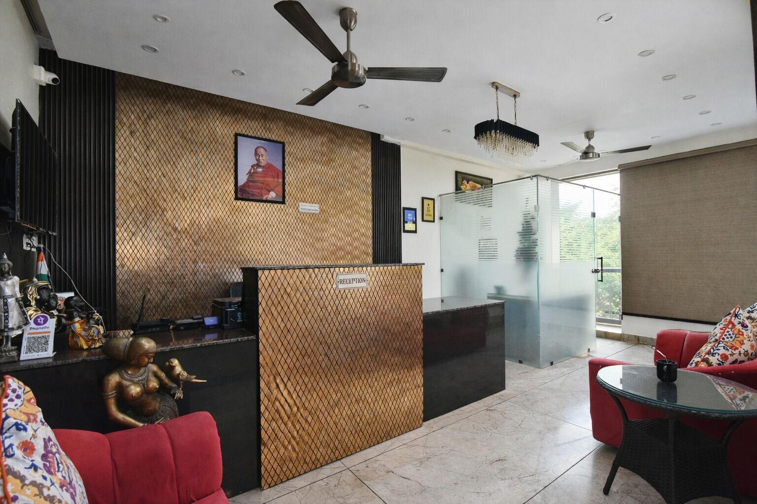 A reception area with a reception desk, a red sofa, a glass table, and ceiling fans.