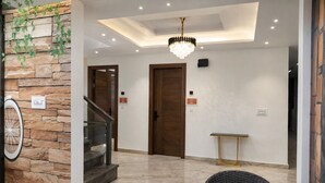 Un intérieur moderne avec un mur en pierre, un escalier, un lustre et des meubles en osier.
