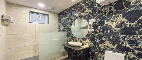 Un baño con pared de mármol, un lavabo con espejo, un inodoro y un secador de pelo en la pared.