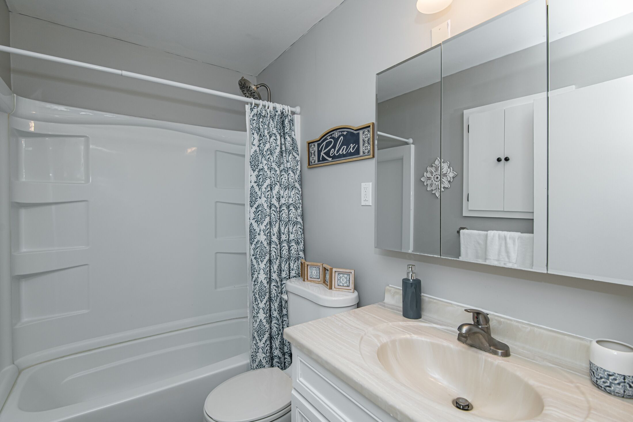 Une salle de bain équipée d’une baignoire, de toilettes, d’un lavabo et d’un miroir sur lequel est inscrit le mot « Détendez-vous ».