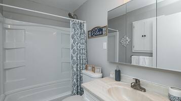 Une salle de bain équipée d’une baignoire, de toilettes, d’un lavabo et d’un miroir sur lequel est inscrit le mot « Détendez-vous ».