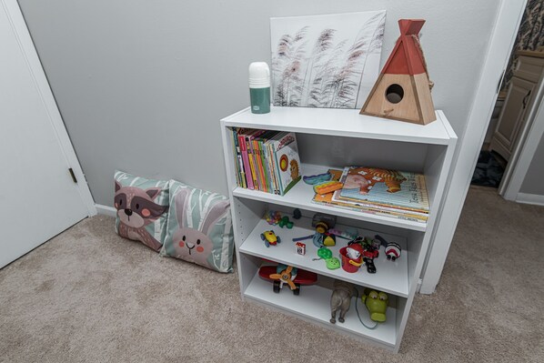 A bookshelf with children's books, toys, and decorative items.