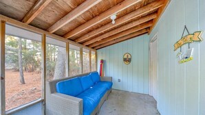 Un portico riparato con un divano in vimini e una ventola a soffitto.