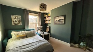 A bedroom with a bed, a desk, a chair, a lamp, and two potted plants. - Dreamy 3BD House W/large Patio - Stoke Newington! (London)