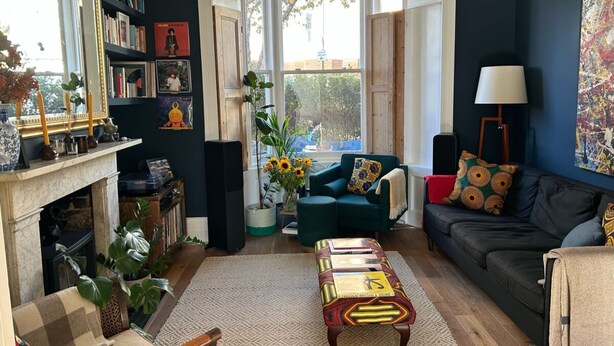 A living room with a fireplace, a green sofa, a coffee table, and a bookshelf. - Dreamy 3BD House W/large Patio - Stoke Newington! (London)