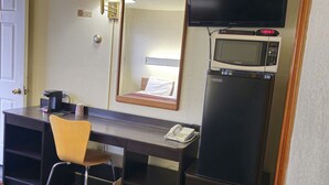 A hotel room with a desk, chair, TV, microwave, and refrigerator. - Home Motel Abbotsford (Abbotsford)