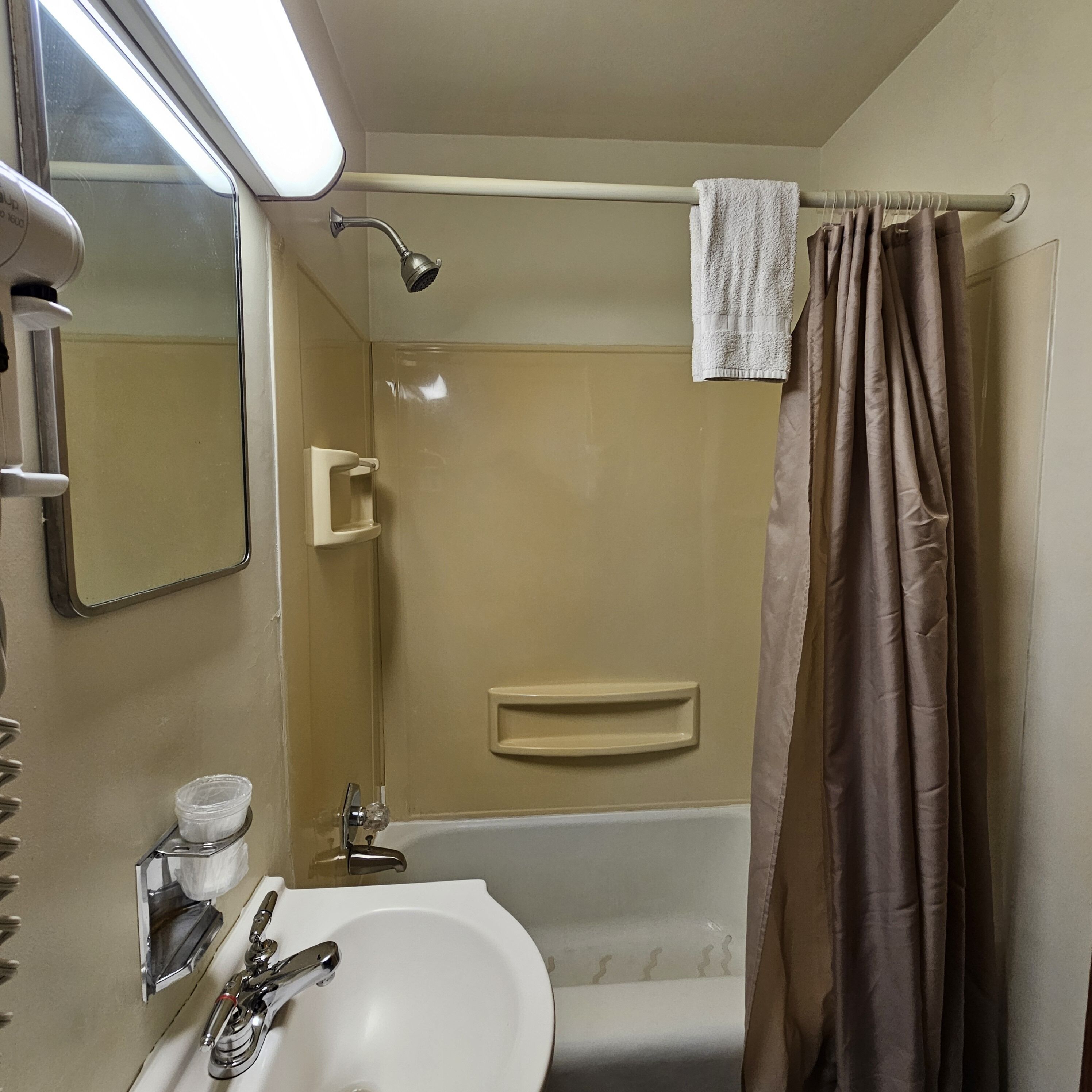 Une salle de bain avec une baignoire, un lavabo, un miroir, une serviette et un rideau de douche.