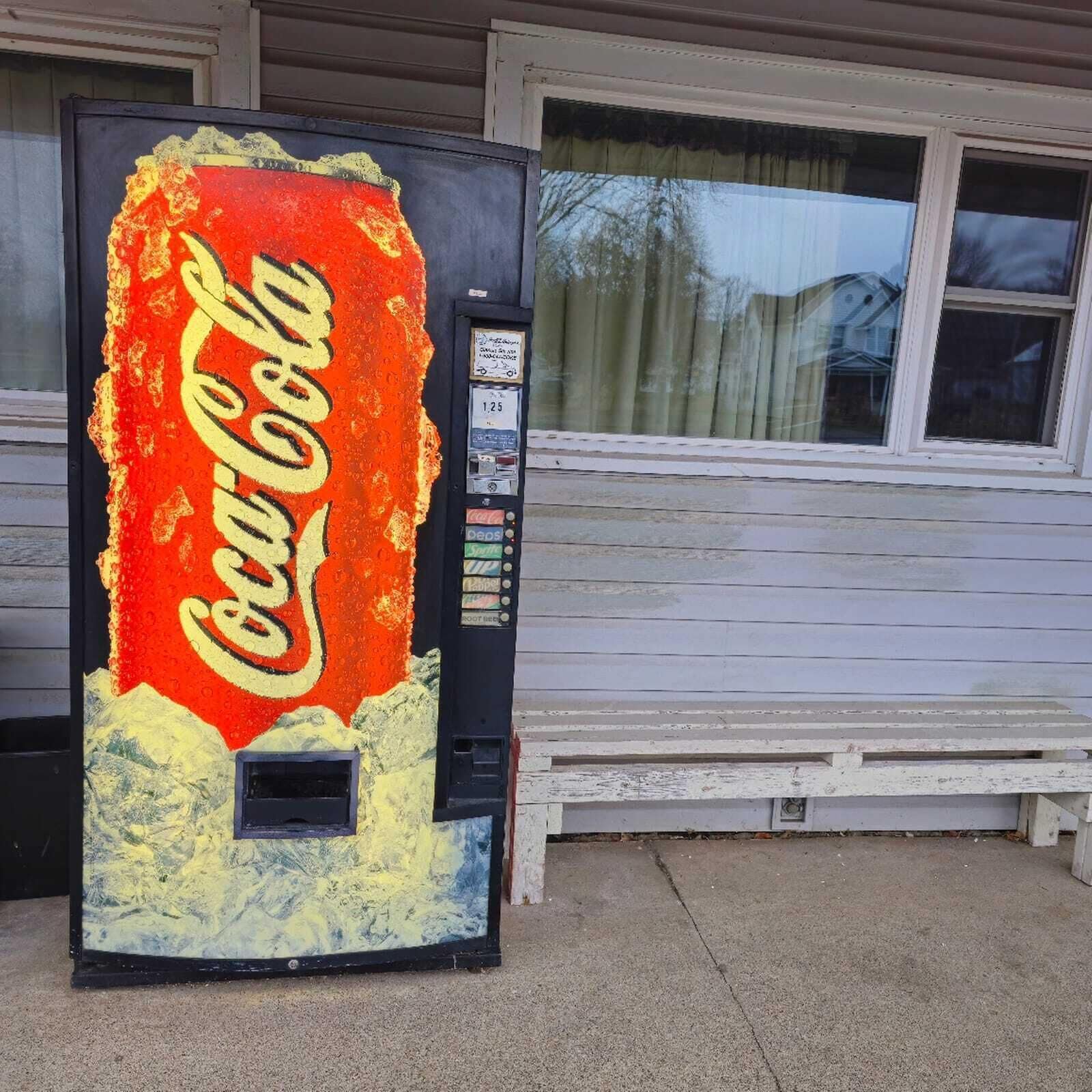 Una máquina expendedora de Coca-Cola frente a una casa.