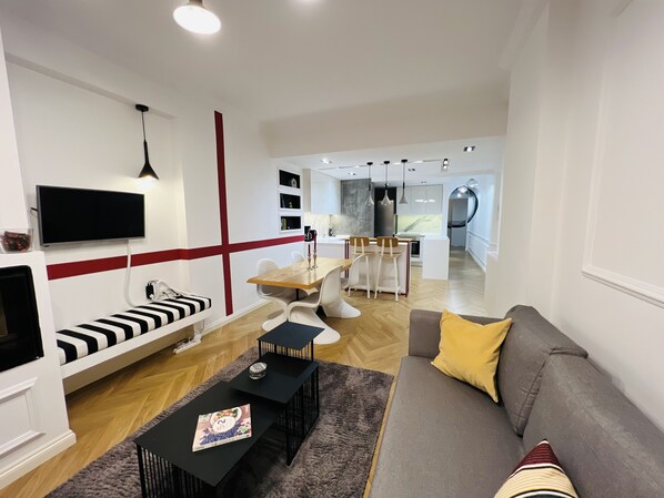 A modern living room with a sofa, a coffee table, and a dining area with chairs and a table.