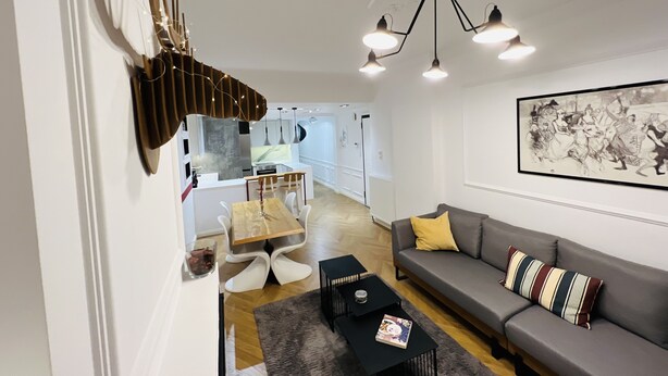 Een moderne woonkamer met een bank, een eettafel en een keuken op de achtergrond.