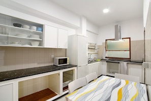 Una cocina con armarios blancos, microondas, fregadero y ventana con vistas.