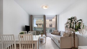 Ein modernes Wohnzimmer mit Essbereich, einer Couch, einem Fernseher und einer großen Kübelpflanze.