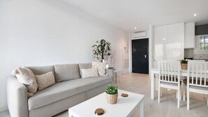 Ein modernes Wohnzimmer mit einer Couch, einem Couchtisch mit einer Pflanze und einem Essbereich mit Stühlen und Tisch.