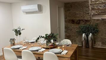 A dining area with a wooden table set for four, white chairs, and a stone wall.
