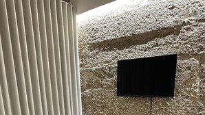 Una sala de estar moderna con un sofá gris, una mesa de centro de madera y una pared con textura de piedra.