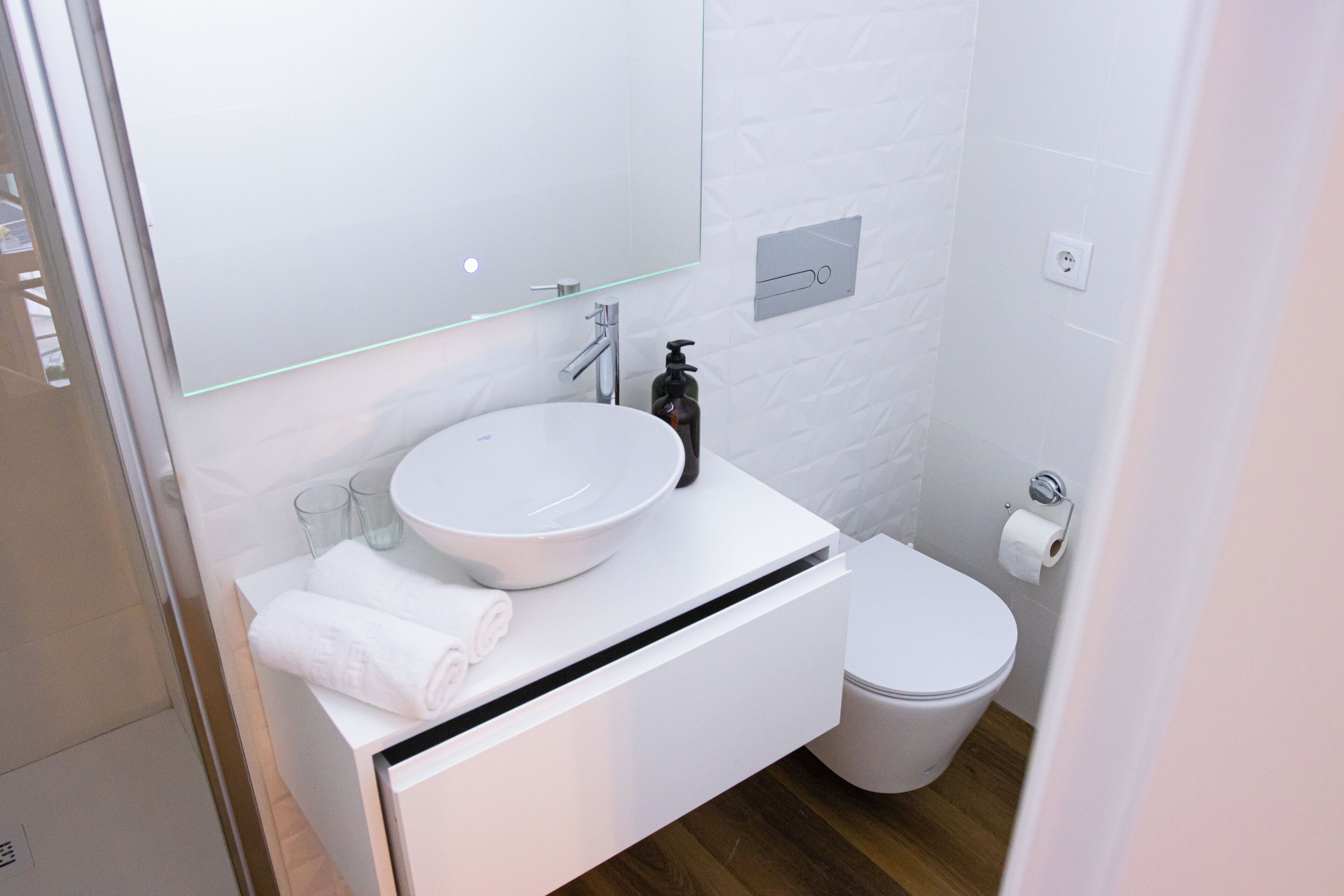 Une salle de bain moderne avec un lavabo blanc, un miroir et des toilettes.