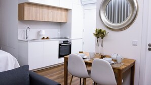 Una cocina compacta con armarios blancos, una encimera de madera y un espejo redondo.