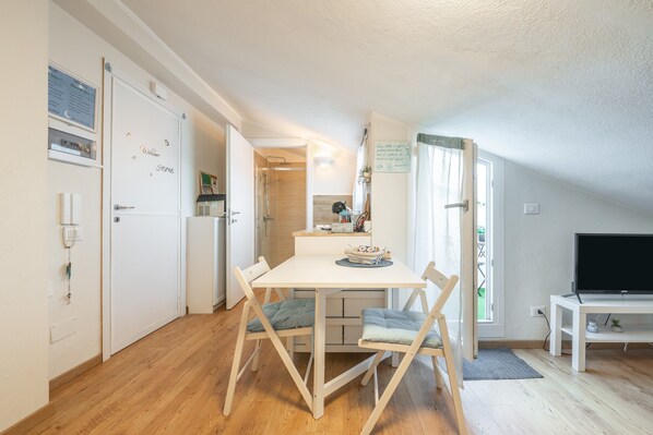 Eine kompakte Küche mit Esstisch, Stühlen, Fernseher und kleinem Kühlschrank.