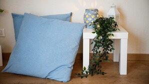 Een witte tafel met een blauw patroon gedecoreerde kandelaar, een witte lantaarn en een groene plant.