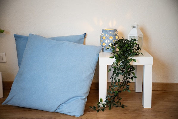 A white table with a blue patterned candle holder, a white lantern, and a green plant.