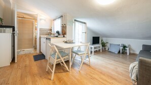 Een knus woongedeelte met kitchenette, eethoek en een bank.