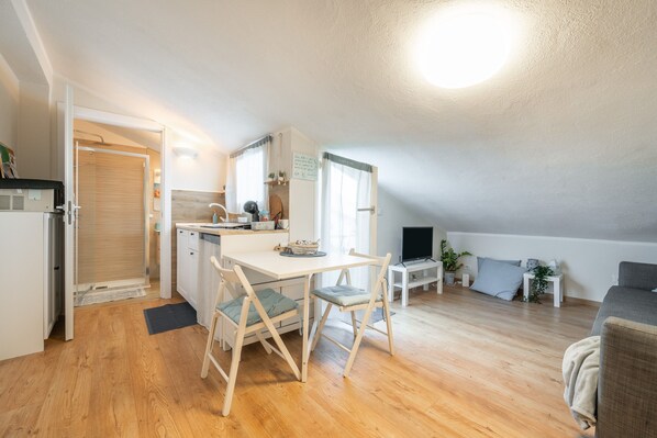 Kompakti oleskelutila, jossa on pieni keittiö, ruokailualue ja sohva.