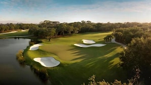 Ein Golfplatz mit Sandbunkern, einem Teich und Bäumen.