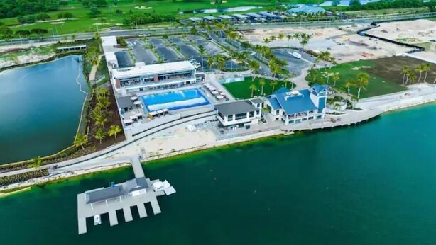 Eine Luftaufnahme eines Küstenhotels mit Schwimmbad, einer Anlegestelle und einem großen Gebäude mit blauem Dach.