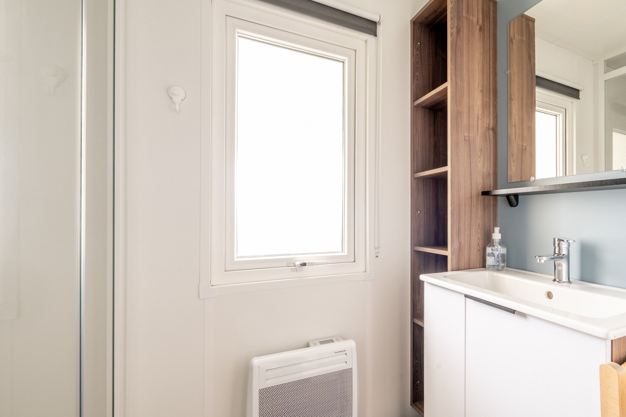A bathroom with a white radiator, a white sink, and a mirror above it.