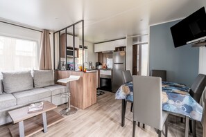 Un espace de vie compact comprenant un canapé, une table à manger, un coin cuisine et un téléviseur à écran plat.