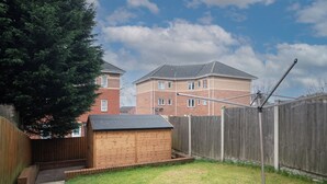 A backyard with a wooden shed, a brick house, and a wooden fence. - Newly refurbed 5 bed house with Free Parking n Dryer (Birmingham)