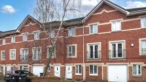 A row of red brick townhouses with white-framed windows and doors, a tree in front, and a parked car. - Newly refurbed 5 bed house with Free Parking n Dryer (Birmingham)