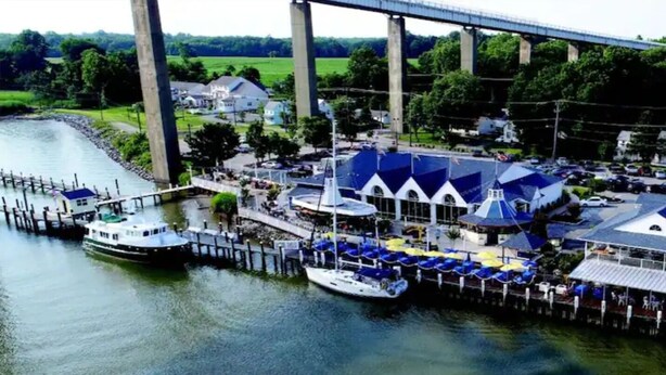 A riverside dock with boats, a covered seating area, and a bridge in the background. - Historic Chesapeake City Stay   (Chesapeake City)