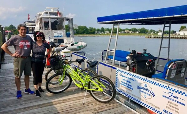 Un muelle con un barco, una bicicleta y un cartel para el ferry de Chesapeake City.