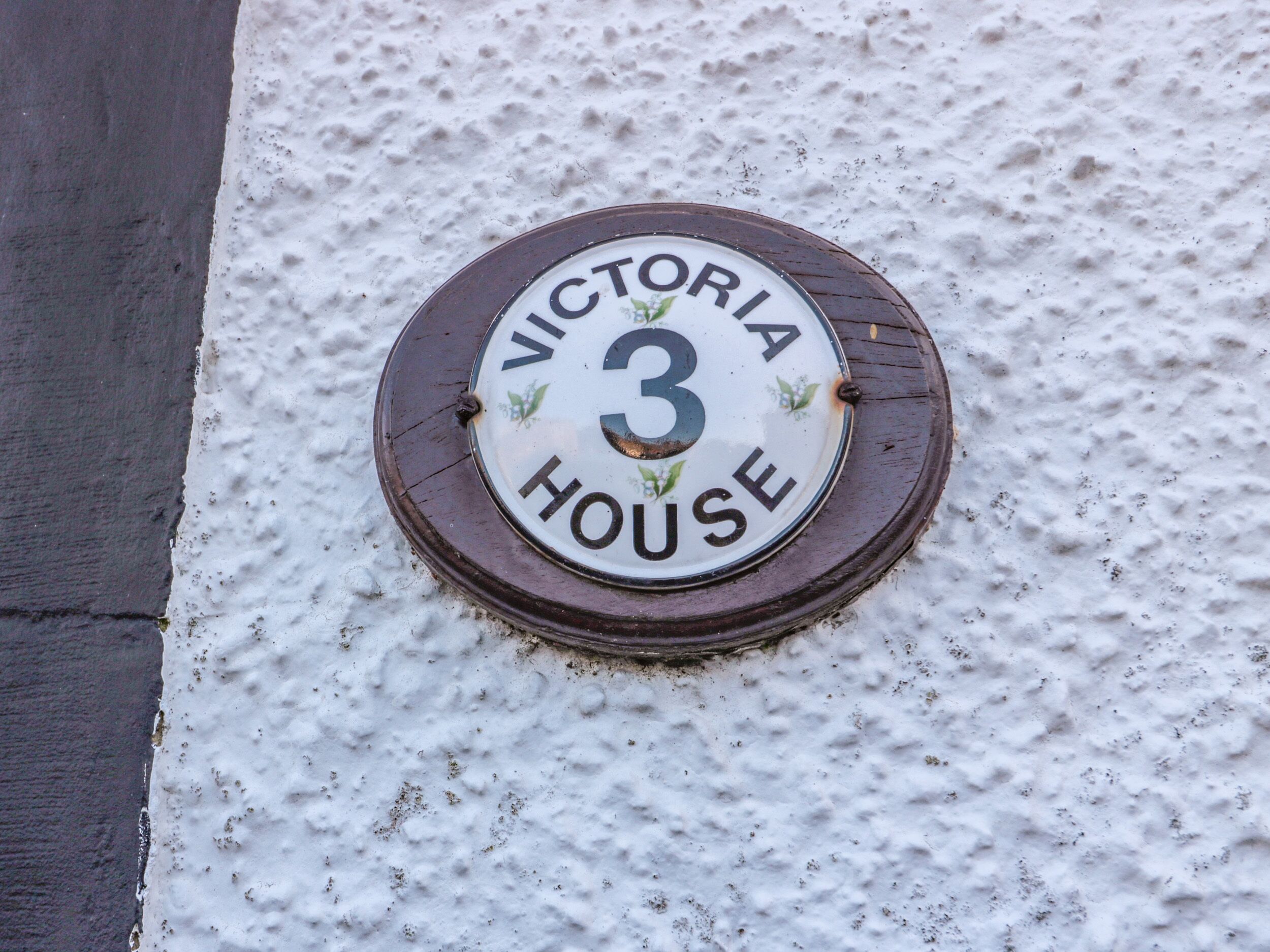 A house number plaque on a textured wall, indicating "VICTORIA HOUSE 3".
