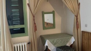 A small, cozy room with a bed, a radiator, and a window with curtains. - Auberge des Cascades  (Imouzzer Ida Ou Tanane)
