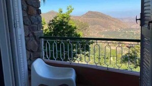 A balcony with a view of mountains, a stone wall, and a white plastic chair. - Auberge des Cascades  (Imouzzer Ida Ou Tanane)